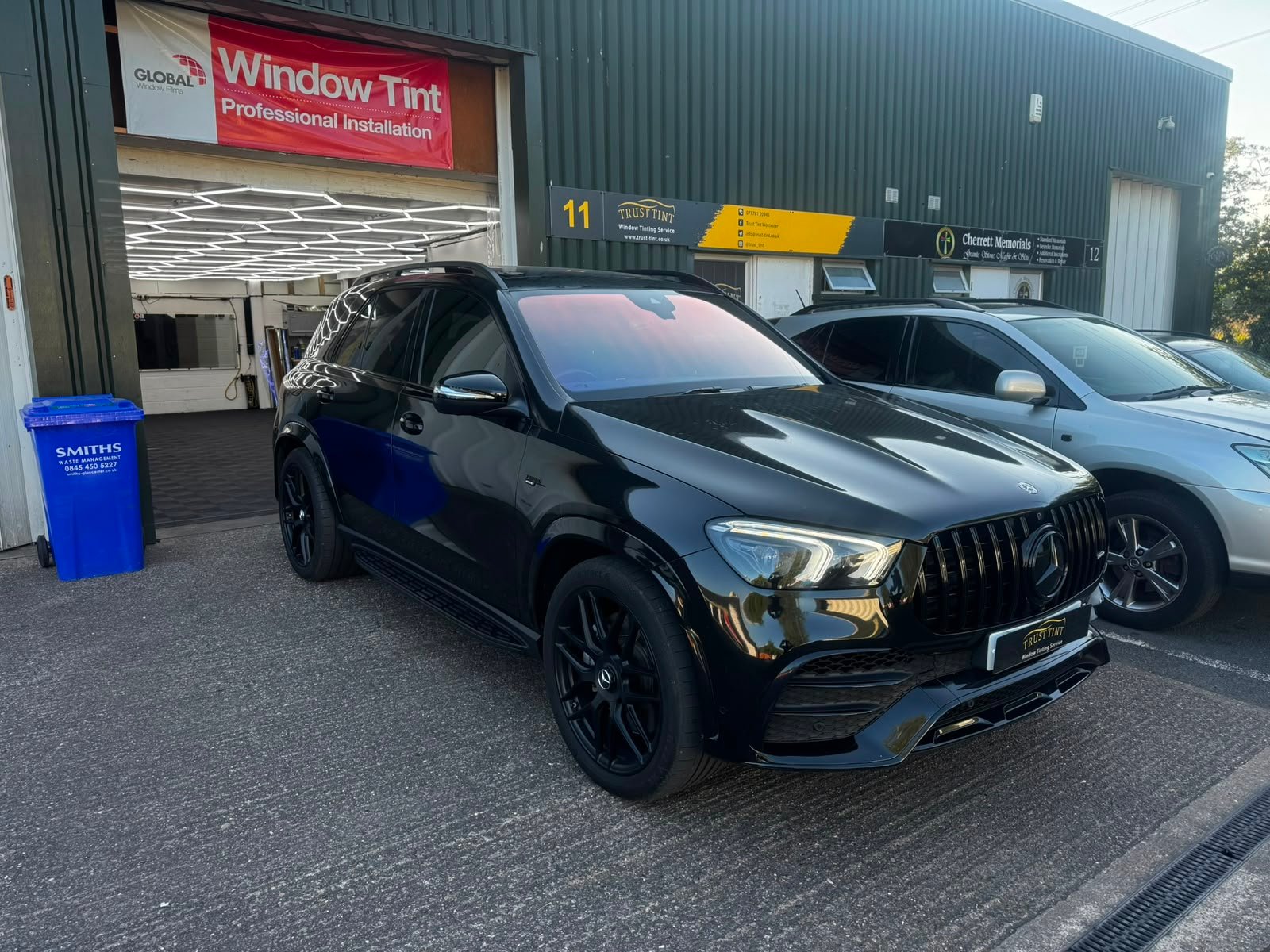 A black Mercedes-AMG GLE with tinted windows, parked outside the Trust Tint workshop at Unit 11 in Worcester